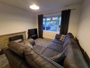a living room with a brown leather couch and a television at 6 beds sleeps 8 detached house with private drive in Upper Penn