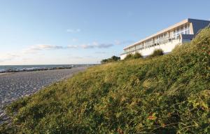 a building on a beach next to a grassy hill at Appartement Seestern D in Schönhagen