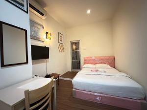 1 dormitorio con 1 cama, escritorio y TV en The Explorers Guesthouse and Hostel en Kuala Lumpur