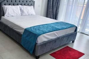 a bedroom with a bed with a blue blanket on it at Georgia Apartments - A Cozy Brand New Apt… in Mombasa +8 photos