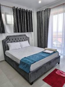 a bedroom with a large bed in front of windows at Georgia Apartments - A Cozy Brand New Apt… in Mombasa