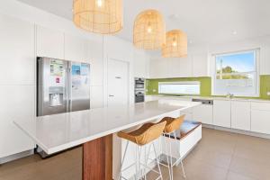 a kitchen with a white counter and two stools at Ebb and Flow Sandy Point Road 70 in Corlette