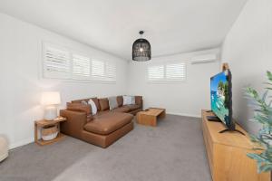 a living room with a couch and a tv at Ebb and Flow Sandy Point Road 70 in Corlette