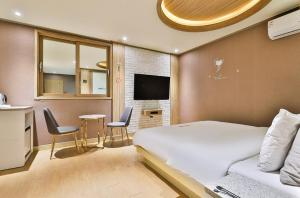 um quarto com uma cama, uma mesa e cadeiras em Time Hotel em Yangsan