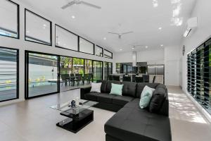 Tiino Villa with Heated Pool Clifton Beach في كليفتون بيتش: غرفة معيشة مع أريكة سوداء وطاولة