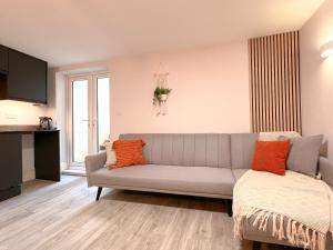 a living room with a gray couch and orange pillows at The Bohemian Basement in Kent
