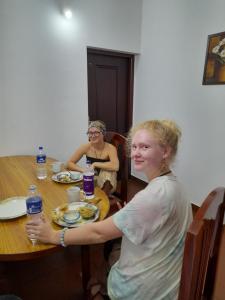 Dos mujeres sentadas en una mesa con una botella de agua en Back Packers Cochin Villa en Kochi