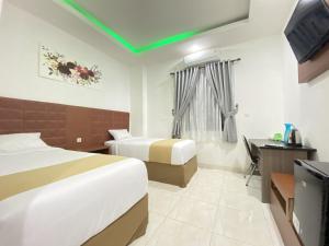 a hotel room with two beds and a flat screen tv at Hotel Tonapa Prince Sorowako Mitra RedDoorz in Malili