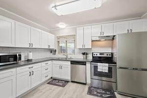 una cocina con armarios blancos y electrodomésticos de acero inoxidable en Elsie House *great family spot* en Las Vegas