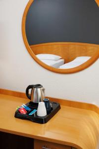a tray with a tea kettle on a table in front of a mirror at OREA Hotel Voro Brno in Brno