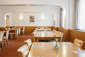 una sala da pranzo con tavoli e sedie in legno di OREA Hotel Voro Brno a Brno