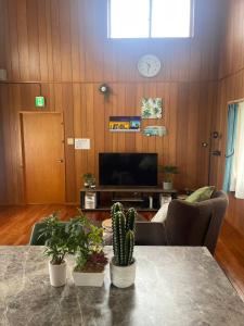 ein Wohnzimmer mit einem Tisch mit Pflanzen darauf in der Unterkunft 川平ハウス in Onna