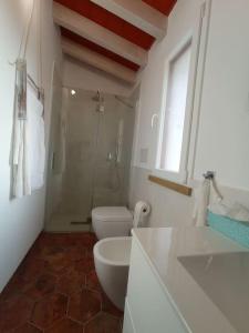 La salle de bains blanche est pourvue de toilettes et d'un lavabo. dans l'établissement Monolocale in campagna vicino Bolgheri e mare, à Cecina
