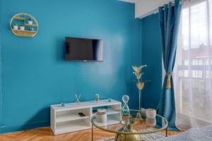 a blue room with a table and a tv on a wall at STUDIO SPA, CENTRE VILLE DE SANNOIS, PARKING PRIVE in Sannois