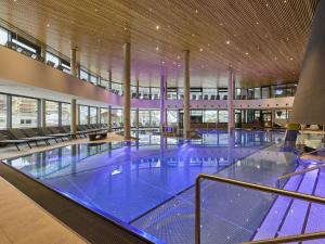 a large swimming pool with blue water in a building at Apartment in Ischgl overlooking the mountains in Ischgl
