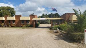 un edificio de ladrillo con una bandera delante de él en Toora Lodge Motel, en Toora