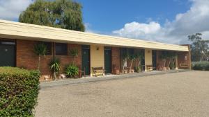 a building with benches and plants in front of it at Toora Lodge Motel in Toora