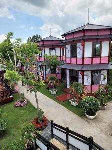 ein rosa und weißes Gebäude mit Bäumen und Blumen in der Unterkunft Homestay Pink House (Ngôi nhà màu hồng) in Ấp Ðông Qứi
