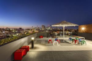 un patio en la azotea con sillas coloridas y sombrilla en Quest Woolloongabba, en Brisbane