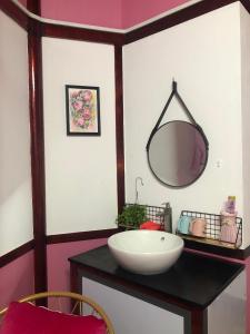 ein Badezimmer mit einem Waschbecken und einem Spiegel auf der Theke in der Unterkunft Homestay Pink House (Ngôi nhà màu hồng) in Ấp Ðông Qứi