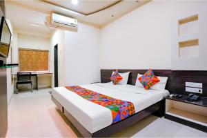 Un dormitorio con una cama y un escritorio en una habitación. en FabHotel Regent Inn - Nr SkyWalk Bridge, en Pune
