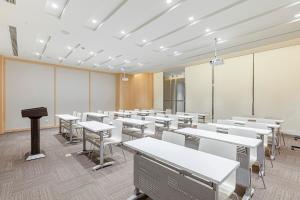an empty classroom with tables and white desks at JI Hotel Shanghai Songjiang Sports Center in Songjiang