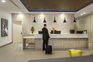 a man with a suitcase standing at a counter at Quest Woolloongabba in Brisbane