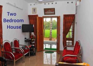 a living room with two chairs and a television at Kuttickattil Pool Home Stay Kumarakom in Kumarakom