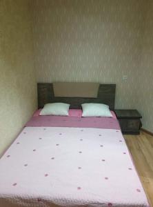 1 dormitorio con 1 cama grande con sábanas rosas y almohadas blancas en Срочно Сдаётся!!!, en Tiflis