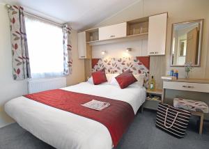 ein Schlafzimmer mit einem großen Bett mit einer roten Decke in der Unterkunft Swanage Coastal Park in Swanage