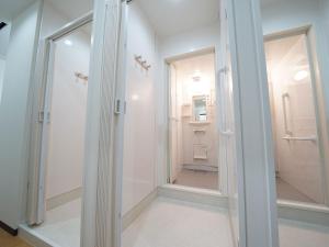 uma casa de banho com uma cabina de duche ao nível do chão e um espelho. em WELLCABIN TENJIN - Male Only em Fukuoka