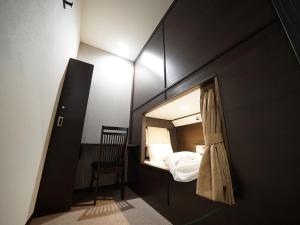 um pequeno quarto com uma cama e uma cadeira em WELLCABIN TENJIN - Male Only em Fukuoka