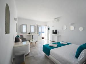 a white bedroom with a bed and a living room at Vitsentzos Suites in Imerovigli