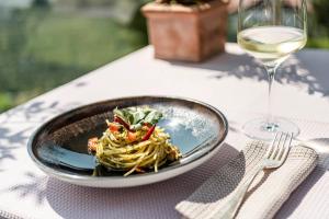 a plate of pasta on a table with a glass of wine at Hotel Rosengarten (Schenna Resort) in Schenna