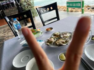een persoon die zijn handen omhoog houdt voor een tafel met eten bij Nancy Grand Villa seaview 2 in Vung Tau