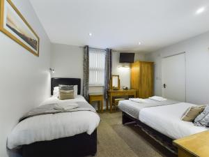 a bedroom with two beds and a desk at Pearl Suite in Blackpool