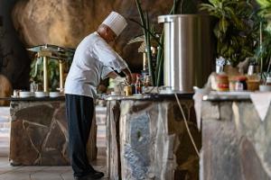 a chef standing in a kitchen preparing food at Gooderson Leisure Natal Spa Self Catering and Timeshare Resort in Paulpietersburg