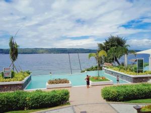 un hombre y una mujer parados frente a un cuerpo de agua en Kembali CONDO Resort with Sea View, en Davao City