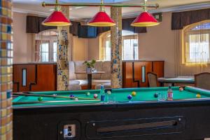a pool table in a living room with red pendant lights at Hotel Kiss in Tata