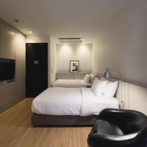 a bedroom with a large bed and a black chair at The Sayla hotel(Baan Sayla) in Chiang Mai
