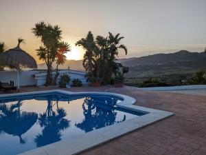 a swimming pool with a sunset in the background at Villas del Alba in Alhaurín de la Torre