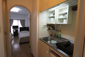 uma cozinha com um lavatório e um quarto com uma cama em Weekly Green In Namba em Osaka