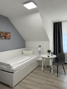 ein weißes Zimmer mit einem Bett und einem Tisch in der Unterkunft Hotel-Fritz in Valwig