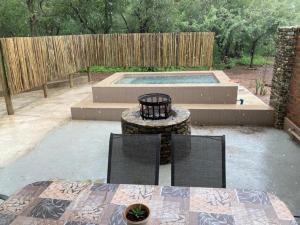 a patio with a table and two chairs and a pool at Locust Retreat in Marloth Park in Marloth Park