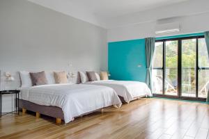 two beds in a room with blue walls and wooden floors at 日月潭水舍民宿 Water House in Yuchi