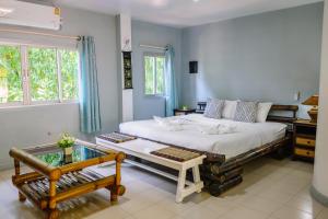 a bedroom with a large bed with a bench and a window at JOP in Ko Chang