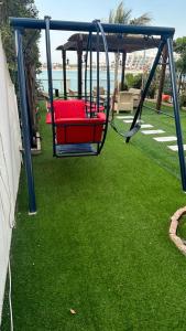 a swing in a yard with green grass at فيلا بشاطئ خاص ومسبح in Durat Alarous