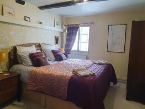 a bedroom with a bed with purple sheets and a window at The Poop Deck in Upton upon Severn