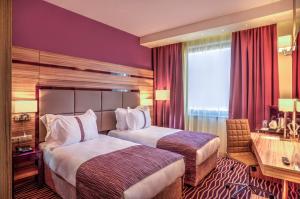 プロブディフにあるHoliday Inn Plovdiv, an IHG Hotelのベッド2台とデスクが備わるホテルルームです。