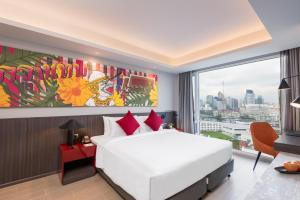 een slaapkamer met een wit bed en een groot raam bij Maitria Hotel Rama 9 Bangkok - A Chatrium Collection in Bangkok